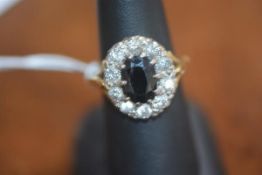 A yellow metal and white metal mounted oval sapphire ten stone diamond cluster ring, total diamond