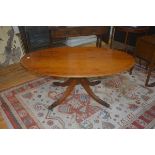 A reproduction yew wood oval coffee table, the plain top with reeded edge, on turned column