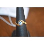 A lady's dress ring set with a single blue stone on yellow metal band marked 750