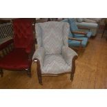An Edwardian upholstered arm chair on turned legs with brass and china castors