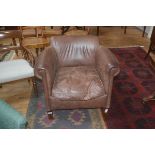 A brown leather upholstered tub chair, on square supports