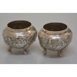 A pair of Eastern circular salt cellars, stamped 866, with seated figure chased decoration, on pad f