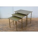 A 1950s nest of three brass coffee tables with inset gilt leather skivers on fluted tapered supports