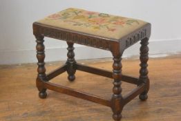 A 1920s Jacobean Revival oak stool with inset tapestry top and arcaded frieze, on turned bobbin supp