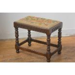 A 1920s Jacobean Revival oak stool with inset tapestry top and arcaded frieze, on turned bobbin supp