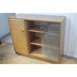 A 1950s walnut bookcase with rectangular top, fitted twin sliding glazed panels, enclosing a shelved