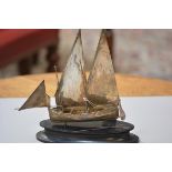 A white metal model of an Arab dhow, complete with hardwood stand, sails etc. (h. 20cm including sta