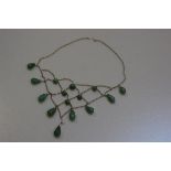 A white metal wire spider's web style pendant necklace mounted with nephritic tear drop shaped beads