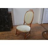 A 19thc oak framed rocking chair with oval upholstered panel back and stuffover seat, on turned supp
