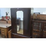 A 1920s mahogany wardrobe, the moulded cornice above a shaped inset mirror panel door above a single