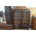 A 1920s oak ledgeback bookcase, the top with moulded edge above a pair of twin leaded glass panel do