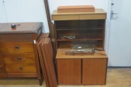 A mid century teak three part modular shelving system including a bookcase top with twin sliding gla