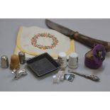 A horn handled knife, an embroidered 1930s handkerchief case, two china thimbles, two silver thimble