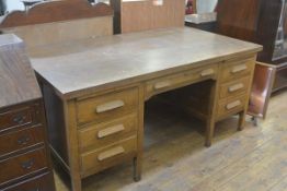 A 1920s Civil Service oak twin pedestal kneehole desk, the rectangular top with centre frieze drawer