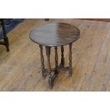 A 1920s oak circular occasional table with flip top, raised on folding turned baluster supports (h.