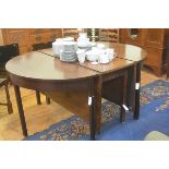 A George III mahogany double D end and centre twin drop leaf extending dining table, the top with mo