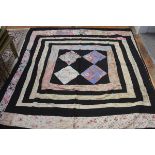 A 1920s reversable black cotton and floral and rose pattern fabric patchwork quilt, the centre with