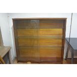A 1970s teak upright open bookcase fitted three glass shelves with twin sliding glass panel doors,