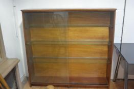 A 1970s teak upright open bookcase fitted three glass shelves with twin sliding glass panel doors,