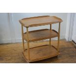 An Ercol light elm three tier trolley with part moulded edges, raised on turned supports, with