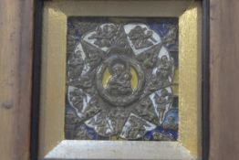 An enamelled brass icon style panel with central Madonna and Child enclosed within a radiating