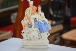 A 19thc Staffordshire flatback figure group, The Poor Man's Clock, decorated with polychrome enamels