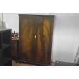 A 1920s/30s flame mahogany two door wardrobe, the moulded cornice above a pair of panel doors