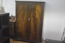 A 1920s/30s flame mahogany two door wardrobe, the moulded cornice above a pair of panel doors
