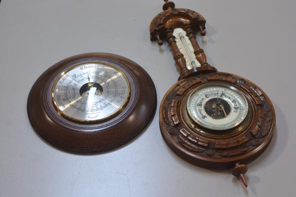 An Edwardian walnut circular aneroid wall barometer complete with thermometer, with carved border