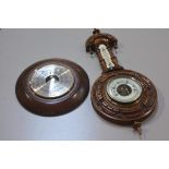 An Edwardian walnut circular aneroid wall barometer complete with thermometer, with carved border