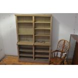 A 19thc stripped and limewashed two section upright open bookcase, the moulded top above an
