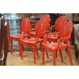A set of four plus one moulded red acrylic open arm dining/side chairs with oval backs, raised on