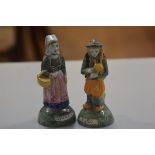 A pair of Quimper figures, a Man with Bagpipes and a Woman with Shopping Basket, decorated with