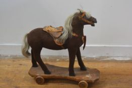 A 19thc child's horse trundle toy with leather saddle, part bridle in felted mohair, with