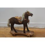 A 19thc child's horse trundle toy with leather saddle, part bridle in felted mohair, with