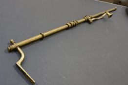 A 19thc brass portiere complete with brass wall fixing and twelve original curtain rings, with