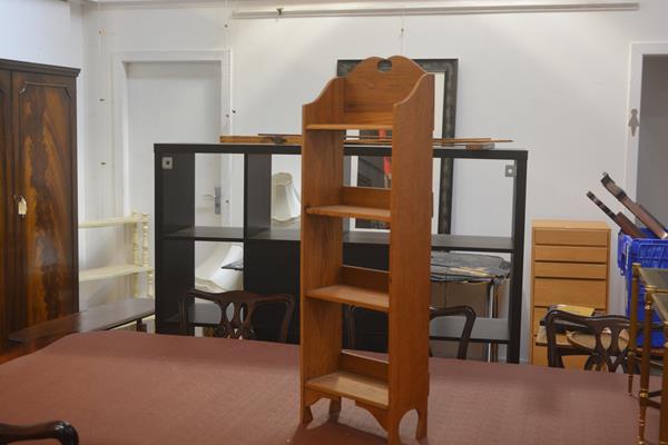 A neat Edwardian oak upright open bookcase, the broken pediment above four shelves, with shaped side