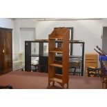 A neat Edwardian oak upright open bookcase, the broken pediment above four shelves, with shaped side