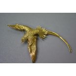 An 18ct gold textured bird of paradise brooch with inset diamond eye, stamped 18k. (l. 8.5cm) (10.