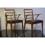 A pair of mid century teak ladderback open carver chairs with original vinyl seats, raised on turned