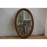 A 1920s oak oval bead and dart bevelled frame wall mirror (88cm x 49cm)