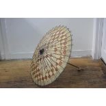 A Japanese parasol with bamboo handle and paper shade decorated with handpainted stylised leaves