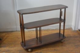 An Ercol elm three tier oval stand/trolley raised on twin end spindle supports, with original ball