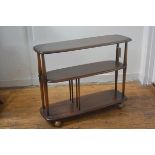 An Ercol elm three tier oval stand/trolley raised on twin end spindle supports, with original ball