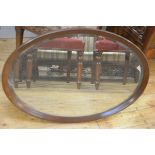 An Edwardian mahogany oval framed wall mirror with bevelled glass plate (l. 78cm x 53cm)