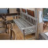 A weathered slatted garden bench. Length 172cm