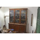 A mid-Victorian oak bookcase cabinet, the moulded cornice over three glazed doors enclosing