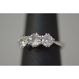 A three stone diamond ring, the round brilliant-cut stones claw set on a tapering platinum band,