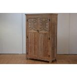 A limed oak wardrobe, c. 1920, with moulded cornice above a pair of panelled doors, with relief-