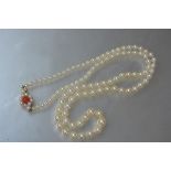 A 9ct gold and coral mounted single strand graduated cultured pearl necklace, the oval gold clasp